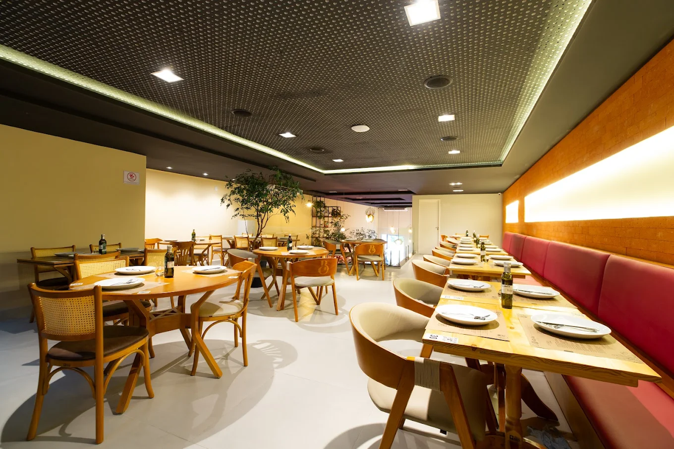 Salão interno do restaurante La Braciera no Tatuapé com mesas de madeira, cadeiras elegantes e iluminação aconchegante.